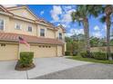 Charming townhome featuring a red tile roof, two-car garage, and mature palm trees adding a tropical touch at 2676 Tanglewood Trl, Palm Harbor, FL 34685