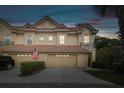 Charming townhome featuring a red tile roof, two-car garage, and well-maintained landscaping at dusk at 2676 Tanglewood Trl, Palm Harbor, FL 34685