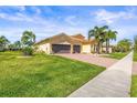Attractive single-story home with a well-maintained lawn, palm trees and brick driveway at 5073 Stone Harbor Cir, Wimauma, FL 33598