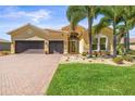 Charming home with tropical landscaping, brick driveway, and a two-car garage at 5073 Stone Harbor Cir, Wimauma, FL 33598