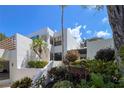 Beautiful exterior view of a white condo building with tropical landscaping and a sunny sky at 523 Bayport Way # 523, Longboat Key, FL 34228