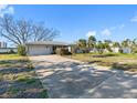 Charming single-story home featuring a two-car garage and beautiful landscaping, complemented by the clear blue sky at 7160 S Shore S Dr, South Pasadena, FL 33707