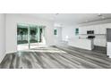 Bright, open-concept living area featuring gray wood floors and sliding glass doors to the outdoor patio at 9763 Crescent Moon Dr, Riverview, FL 33578