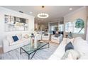 Bright living room with modern light fixture and plush white furnishings at 16201 Muirfield Dr, Odessa, FL 33556