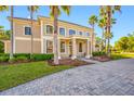 Elegant two-story home with well-manicured lawn, framed by mature palm trees and a paver driveway at 19005 Cour Ests, Lutz, FL 33558