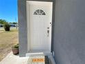 Inviting white front door with decorative window and 'HOME' welcome mat, set against a modern gray exterior at 21298 Austin Ave, Port Charlotte, FL 33952