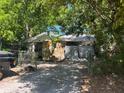 Exterior of house featuring a stone facade, banana tree, covered entrance, and tarped car port at 2610 E 26Th Ave, Tampa, FL 33605