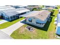 Aerial view of a well-maintained home with a long driveway and carport, surrounded by lush greenery at 5745 Pawnee St, Zephyrhills, FL 33542