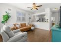 Bright living room featuring hardwood floors, comfortable seating, ceiling fan, and a view into the kitchen at 6920 N Hubert Ave, Tampa, FL 33614