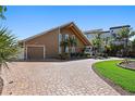 Charming two-story home with a brick driveway, attached garage, and lush tropical landscaping at 1101 Bay Pine Blvd, Indian Rocks Beach, FL 33785