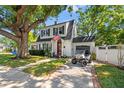 Charming two-story home with a well-manicured lawn, mature trees, a red front door, and a golf cart at 2833 7Th N St, St Petersburg, FL 33704