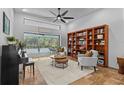 Cozy living room with travertine floors, built-in shelving, neutral furniture, and view of screened pool at 3267 Westcott Ct, Palm Harbor, FL 34684