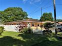 Well-manicured lawn and landscape surround this yellow single-story home featuring a charming white picket fence at 8210 Marigold Ave, Tampa, FL 33614