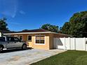 A yellow single-story home with a well-manicured lawn and privacy fence is shown on a sunny day at 8210 Marigold Ave, Tampa, FL 33614