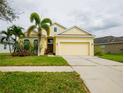 Charming yellow single-Gathering home featuring a two-car garage and lush landscaping at 12720 Whitney Meadow Way, Riverview, FL 33578