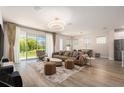 Bright living room with a modern light fixture, light wood floors, neutral walls, and a view of the backyard at 1439 Gopher Loop, Tarpon Springs, FL 34689