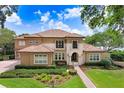 Beautiful exterior of a tan two-story home with a terracotta roof and manicured landscaping at 17111 Journeys End Dr, Odessa, FL 33556