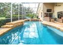 Inviting screened-in pool area with a waterfall feature, jacuzzi, and ample seating for outdoor relaxation at 17503 Edinburgh Dr, Tampa, FL 33647