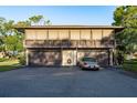 Two-story home with a balcony and three garage spaces, alongside an elegant gold convertible parked in the driveway at 2934 Lichen Ln # D, Clearwater, FL 33760