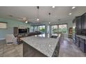 Open-concept kitchen and living room featuring a large granite island, tile flooring, and stainless steel appliances at 6338 Springline Pl, Apollo Beach, FL 33572