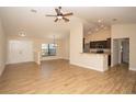 Bright and airy living room featuring wood floors, a ceiling fan, and a view into the kitchen at 6527 Grapewood Rd, Spring Hill, FL 34609