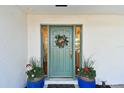 Charming home entrance featuring a green door flanked by planters and a wreath at 1887 Oak Forest E Dr, Clearwater, FL 33759