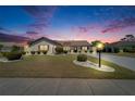 Charming single-Gathering home with manicured lawn and landscaping illuminated by outdoor lighting at twilight at 2007 E View Dr, Sun City Center, FL 33573