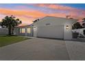 Exterior view of a single-story home at sunset, featuring an attached garage and manicured landscaping at 2650 E Vina Del Mar Blvd, St Pete Beach, FL 33706