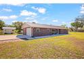 Charming single-story brick home with a metal roof, a long driveway, and a storage shed at 8122 Ehren Cemetery Rd, Land O Lakes, FL 34639