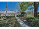 Charming single-story home with a well-maintained yard, complemented by mature trees and a bright blue sky at 1333 Shady Pine Way # F, Tarpon Springs, FL 34688