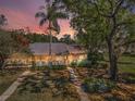 A single-story home featuring a fenced yard and mature trees, all bathed in the soft glow of a colorful sunset sky at 1333 Shady Pine Way # F, Tarpon Springs, FL 34688