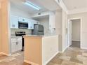 Bright kitchen featuring white cabinets, granite countertops, stainless steel appliances, and a view to the entry hall at 17114 Carrington Park Dr # 207, Tampa, FL 33647
