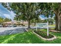 The Village on the Green Club House sign surrounded by flower beds and a large shady tree at 2537 Royal Pines Cir # 19I, Clearwater, FL 33763