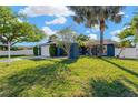Landscaped front yard featuring a single story blue home, shade trees, a lawn, and a two car garage at 6208 Imperial Ky, Tampa, FL 33615