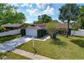 A single-story blue home with a manicured lawn, mature landscaping, and a paved driveway leading to an attached garage at 6208 Imperial Ky, Tampa, FL 33615