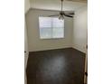 A naturally lit room with neutral walls, wood-look tile floors, a ceiling fan, and a large window at 7252 Seedpod Loop, Wesley Chapel, FL 33545