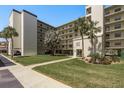 Condo building exterior with a lush green lawn, mature palm trees, and covered parking spaces at 9860 62Nd N Ter # 1051, St Petersburg, FL 33708