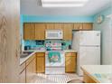 Functional kitchen featuring wooden cabinets, white appliances, and natural lighting at 11135 Carriage Hill Dr # 5, Port Richey, FL 34668
