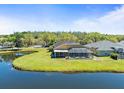 Backyard featuring a screened-in porch overlooking a serene pond and lush green lawn at 19230 Wind Dancer St, Lutz, FL 33558