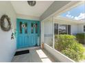 Charming entryway featuring a vibrant blue front door and a welcoming covered porch area at 22322 Tennyson Ave, Port Charlotte, FL 33954