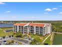 Low-angle view of multi-story condo with manicured grounds, parking and tranquil lake at 234 Mariner Dr # 234, Tarpon Springs, FL 34689