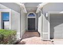 Inviting entryway featuring a decorative front door, textured walls, and red brick walkway leading to the garage at 24941 Ravello St, Land O Lakes, FL 34639