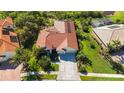 Aerial view showcasing a well-maintained home with a red tile roof, solar panels, lush landscaping, and a spacious driveway at 4499 Chase Oaks Dr, Sarasota, FL 34241