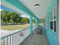 Relaxing covered porch with tiled flooring, white railing, and views of the expansive lawn at 6418 Austrian Blvd, Punta Gorda, FL 33982