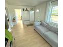 Bright living room featuring a gray couch, hardwood floors, and ample natural light from the large windows at 801 53Rd N Ter, St Petersburg, FL 33703