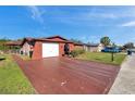 Wide driveway with a view of the one-story home, landscaping and blue sky at 10035 Cherry Creek Ln, Port Richey, FL 34668