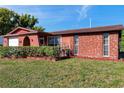 Charming one-story home with manicured lawn and unique rock exterior and bright blue sky at 10035 Cherry Creek Ln, Port Richey, FL 34668