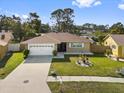 An eye level exterior view of a tan single story home with a manicured green lawn and driveway to a two car garage at 11803 70Th St, Largo, FL 33773