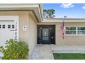 Close up of the front of a tan single story home with an American flag and black framed screen door at 11803 70Th St, Largo, FL 33773