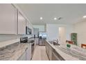 Kitchen featuring granite counters, an island with stainless steel sink, stainless steel appliances, and grey cabinets at 1504 Colt Creek Pl, Wesley Chapel, FL 33543